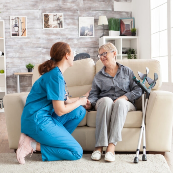 happy-old-woman-nursing-home-sitting-couch-talking-with-her-caretaker-retired-woman-with-crutches-1024x683 (1)